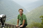 Portrait of mid adult man sitting on viewing platform, New River Gorge National River, Fayetteville, West Virginia, USA