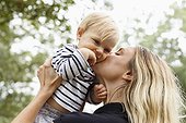 Mother kissing baby girl on cheek, outdoors