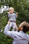 Father holding baby girl in air, outdoors