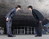 Two Businessmen Bowing in Front of Office Building