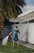 Stylish Young Woman Watering Lawn