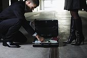 Man Looking Through Briefcase of Cash and Documents
