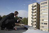 Businessman Aiming Audio Surveillance Equipment into Apartment Building