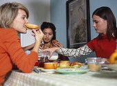 Three young women sitting at breakfast table