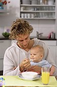Father sitting in kitchen, feeding baby