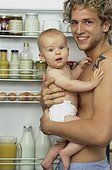 Father holding baby, standing in front of open fridge