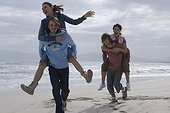 Two Couples Riding Piggyback on Beach