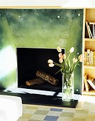 A flower vase is kept beside the fireplace