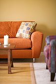 Orange suede couch in yellow hardwood living room
