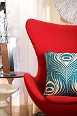 A patterned throw pillow on a contemporary red wing chair