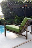 A cushioned chaise is placed near the swimming pool in the patio