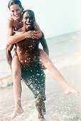 Young man carrying a woman piggyback in the sea