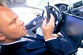 Businessman sitting with mobile phone and laptop in a car