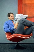 businessman sits in a chair and reading the news paper