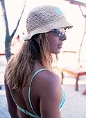 Young woman wearing bikini, sunhat and sunglasses