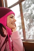Young woman wearing winter clothing looking through window