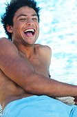 Laughing young man by a swimming pool