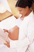 Pregnant woman reading a book in bed