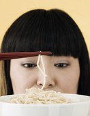 Woman picking up noodle with chopsticks