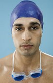 Serious young man wearing swim cap and goggles
