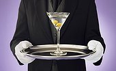 Butler holding a serving tray with a martini on top of it