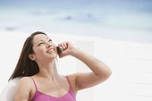 Young woman at the beach talking on a cell phone