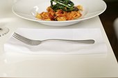 Fork lying next to a plate with tagliatelle