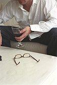 Man holding a Glass of Red Wine and Glasses laying on a Table