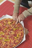 Man (Detail) cutting up a big Pizza