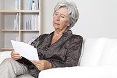 Senior woman reading document on couch