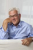 Confident senior man wearing glasses sitting on couch