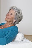 Senior woman listening to music on couch