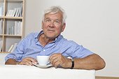 Relaxed senior man with cup of coffee on couch