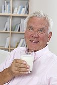 Relaxed senior man with glass of milk on couch