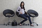Pregnant woman sitting on chair in waiting area