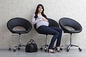 Pregnant woman sitting on chair in waiting area