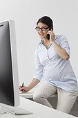 Pregnant woman on the phone in office