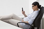 Pregnant woman sitting in office chair looking at telephone