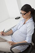 Pregnant woman writing at desk