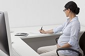 Pregnant woman writing at desk