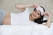 Pregnant woman lying in bed with eye mask