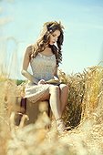 Woman with book and suitcase in cornfield