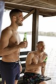 Male friends having beer at lake