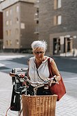 Senior woman standing near bicycle