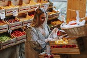 Smiling woman choosing tomatoes in shop