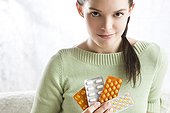 woman holding various blister packs of pills