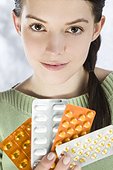 woman holding various blister packs of pills