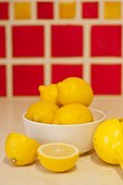 Bowl of lemons on counter with red tiles behind