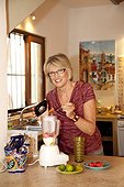 Woman making smoothie in kitchen blender