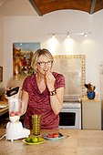 Woman making smoothie in kitchen blender